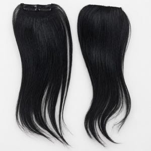 Könnte beinhalten: Zwei glatte, tiefschwarze Haarverlängerungen mit glänzender Oberfläche. Jedes Teil verfügt über einen kleinen, integrierten Metallclip an der Oberseite zur sicheren Befestigung, der so konzipiert ist, dass er sich nahtlos in das Haar einfügt.