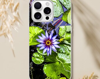 May include: A white phone case with a colorful design featuring a purple water lily with a yellow center surrounded by green lily pads. The phone case has a cutout for the camera lens.