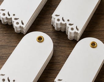 May include: Four stacks of white paper tags with rounded tops and decorative die-cut scalloped edges at the bottom. Each tag features a single circular hole reinforced with a metallic gold-colored eyelet, arranged in a grid pattern.