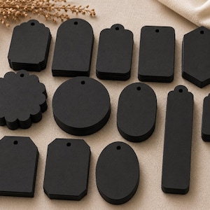 May include: A collection of black paper tags in various shapes including circles, rectangles, ovals, and scalloped edges. Each tag features a single pre-punched hole at the top for stringing. The set includes multiple stacks of uniform shapes.