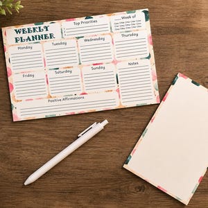 May include: A weekly planner notepad with a colorful polka dot border, featuring sections for days of the week, top priorities, notes, and positive affirmations, accompanied by a white ballpoint pen and a blank notepad with a matching border.