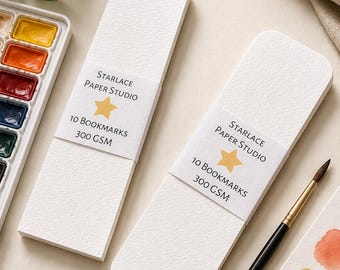 May include: Two rectangular white paper bookmarks with rounded corners, each wrapped in a paper band labeled Starlace Paper Studio with a yellow star icon, 10 Bookmarks, and 300 GSM. The bookmarks have a textured surface and are blank.