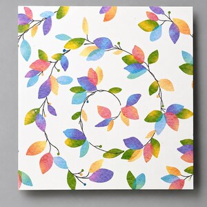 May include: A square print featuring a spiral pattern of watercolor-style leaves in shades of blue, purple, yellow, orange, and green. The leaves are arranged along thin, dark, curved stems against a solid white background.