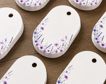 May include: A collection of oval-shaped white paper tags, each featuring a pre-punched hole at the top. The tags are decorated with a printed botanical pattern of purple lavender sprigs and small flowers arranged along the bottom and side edges.