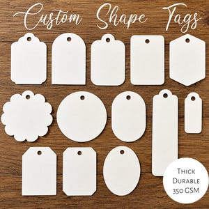 May include: A collection of white paper tags in various geometric shapes, including circles, rectangles, and scalloped edges, each featuring a pre-punched hole. The text Custom Shape Tags and Thick Durable 350 GSM is printed on the image.