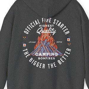 Peut inclure: Un sweat à capuche gris foncé avec un graphique circulaire blanc au dos. Le graphique représente un feu de camp avec des flammes, le texte "OFFICIAL FIRE STARTER", "HIGHEST QUALITY", "CAMPING BONFIRES", et "THE BIGGER THE BETTER".