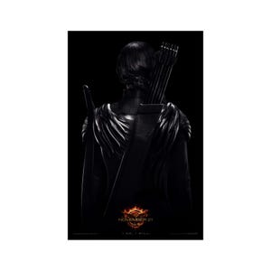 May include: A black and white poster featuring a woman in a black outfit with a bow and arrow strapped to her back. The poster has the text "NOVEMBER 21" and "I AM. I WILL."