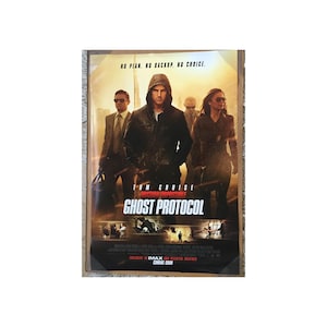 May include: A movie poster for the film "Mission: Impossible - Ghost Protocol" starring Tom Cruise. The poster features a dark background with a cityscape in the distance. Tom Cruise is in the center of the poster, wearing a black leather jacket and looking intensely at the camera. The text "Mission: Impossible - Ghost Protocol" is in large, red letters at the bottom of the poster.