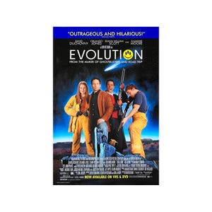May include: Movie poster for the film "Evolution" featuring David Duchovny, Orlando Jones, Seann William Scott, and Julianne Moore. The poster has a blue banner at the top with the film's title and a smiley face. The bottom of the poster says "NOW AVAILABLE ON VHS & DVD."