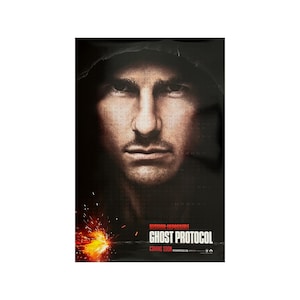 May include: A movie poster for the film "Mission: Impossible - Ghost Protocol". The poster features a close-up of Tom Cruise's face, with a dark hooded jacket and a fiery explosion in the background. The title of the film is written in red text.
