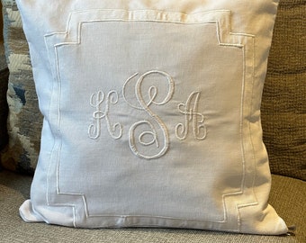May include: White pillow with a white embroidered monogram of the letters "HSA" in a square frame.
