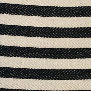 May include: Close-up of a white and black striped fabric with a herringbone pattern. The fabric is woven with a subtle texture.