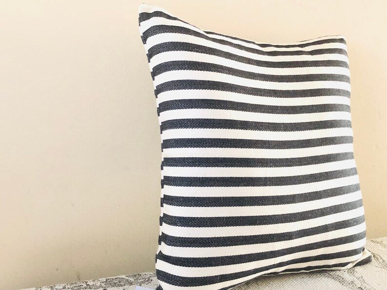 May include: A black and white striped throw pillow with a soft, textured fabric.