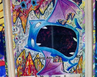 May include: Golbat Pokemon card from the Pokemon Trading Card Game. The card features a purple and blue illustration of Golbat with the text "Golbat" and "Wing Attack" on the card. The card has a HP of 70.