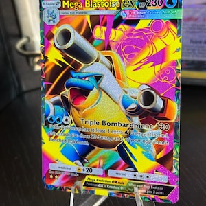 May include: A holographic Mega Blastoise EX Pokémon card. The card features a vibrant design with a blue and white Blastoise character, text that reads "Triple Bombardment 130", and the text "Mega Blastoise EX".