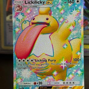 May include: A holographic Lickilicky ex Pokémon card. The card features a yellow creature with a long pink tongue. The card has a HP of 160 and the attack "Licking Fury". The card is displayed on a clear stand.