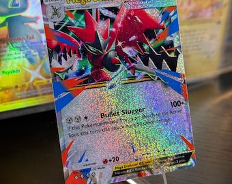 Könnte beinhalten: Eine holografische Mega Scizor EX Pokémon-Karte, präsentiert auf einem transparenten Ständer. Die Karte zeigt eine rote und schwarze Scizor-Illustration mit dem Text "Mega Scizor EX" und "Bullet Slugger". Weitere Karten sind im Hintergrund sichtbar.