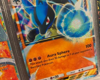 Puede incluir: Una carta de comercio de Pokemon holográfica con Lucario ex, un Pokemon azul y negro con una esfera de aura blanca. La carta tiene una designación de etapa 1 y 150 HP. El ataque de la carta se llama Aura Sphere e inflige 100 daños. La carta también tiene una debilidad contra lucha y una resistencia contra psíquico.
