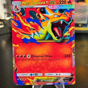 Könnte beinhalten: Eine Pokémon-Sammelkarte von Mega Charizard Y EX. Die Karte zeigt eine lebendige Illustration von Charizard in Rot-, Orange- und Gelbtönen, vor einem blauen und gelben Hintergrund. Der Text auf der Karte lautet "Crimson Dive" und "250".