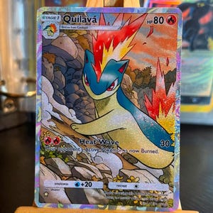 May include: A holographic Pokemon trading card featuring the character Quilava with flames on its head. The card displays the text Quilava, HP 80, Heat Wave, 30, and includes game statistics, a fire energy symbol, and a rocky landscape illustration.