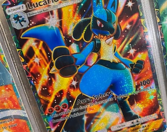 Puede incluir: Una carta coleccionable Pokémon Lucario EX holográfica. La carta presenta un personaje Lucario azul y negro con un pecho amarillo, sobre un fondo naranja y amarillo llameante. El texto de la carta incluye "Aura Sphere" y "HP 150".