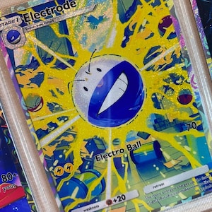 Puede incluir: Una tarjeta coleccionable holográfica con el Pokémon Electrode. La tarjeta tiene una combinación de colores amarillo y azul con el texto "Electrode" en la parte superior. La tarjeta también tiene el texto "Electro Ball" y "+20".