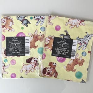 May include: Two sheets of pale yellow gift wrap featuring a repeating pattern of playful puppies in various colours, including brown, black, and white, interspersed with colourful balls and hearts. Each sheet measures 0.76 metres by 1 metre.