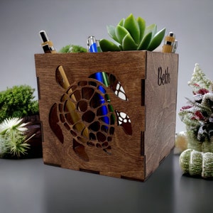 May include: A wooden desk organizer shaped like a turtle with a cutout design. The organizer has a brown stain and is personalized with the name "Beth".