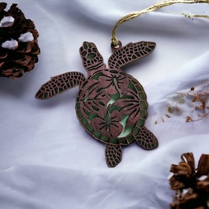 May include: A wooden turtle ornament with a green and brown color scheme. The turtle has a detailed design of flowers and leaves on its shell.