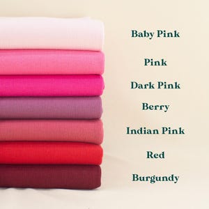 A stack of seven different colored ribbons or fabrics, including Baby Pink, Pink, Dark Pink, Berry, Indian Pink, Red, and Burgundy, arranged in a visually appealing manner.