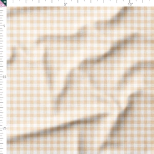 May include: Close-up of a fabric with a classic gingham pattern. The fabric features a repeating pattern of small, evenly spaced squares in a light tan and white color scheme. The fabric is slightly wrinkled, adding texture.