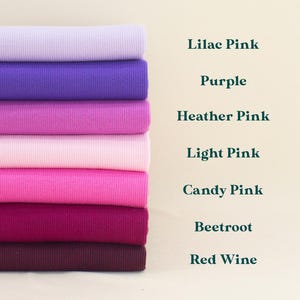 A stack of seven different colored ribbed fabrics, including Lilac Pink, Purple, Heather Pink, Light Pink, Candy Pink, Beetroot, and Red Wine, arranged in a visually appealing manner.