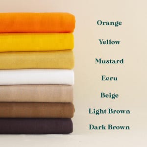 A stack of seven fabric swatches in various colors, including orange, yellow, mustard, ecru, beige, light brown, and dark brown.