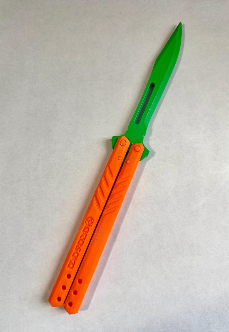 May include: A green and orange butterfly knife with the text "GRITO" on the handle.
