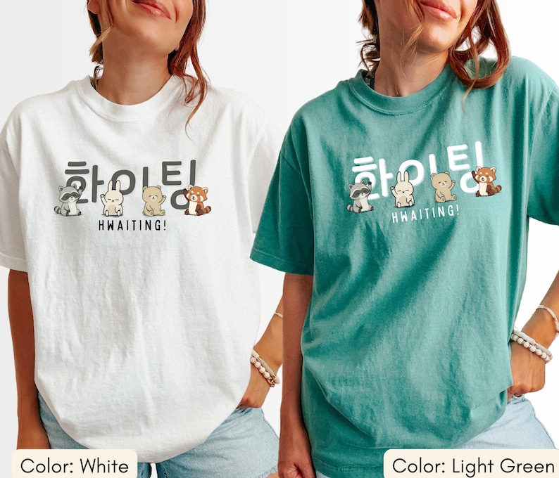 May include: White and light green t-shirts with a graphic design. The design features Korean text and cartoon animals. The text reads "Hwaiting!" and "Hwaiting!" in English. The t-shirts are casual wear.