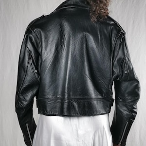 K&ouml;nnte beinhalten: Schwarze Lederjacke mit verk&uuml;rzter Passform und Rei&szlig;verschluss-&Auml;rmelb&uuml;ndchen. Die Jacke hat einen Stehkragen und einen Rei&szlig;verschluss.