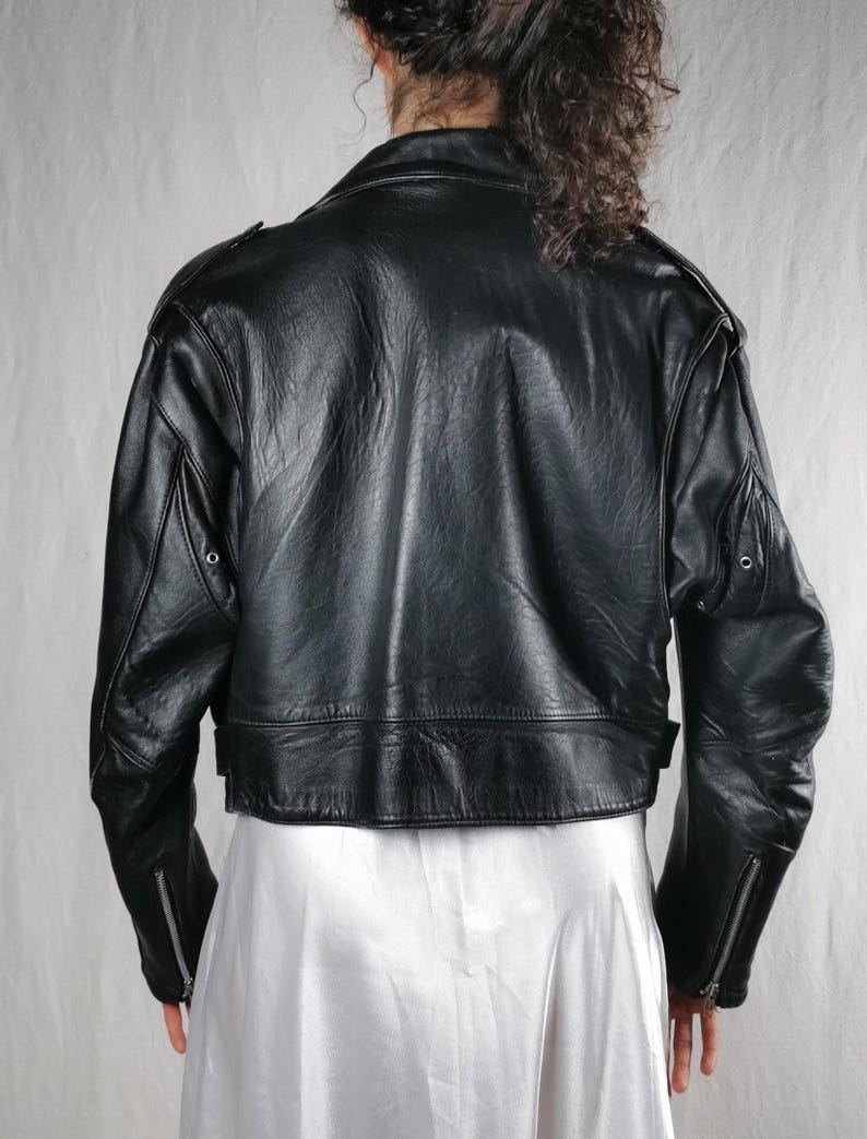 K&ouml;nnte beinhalten: Schwarze Lederjacke mit verk&uuml;rzter Passform und Rei&szlig;verschluss-&Auml;rmelb&uuml;ndchen. Die Jacke hat einen Stehkragen und einen Rei&szlig;verschluss.