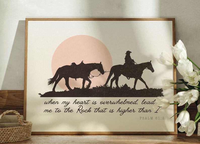 May include: A framed print with a silhouette of two horses and riders against a pink sunset. The text reads "when my heart is overwhelmed, lead me to the Rock that is higher than I" and "PSALM 61:2".