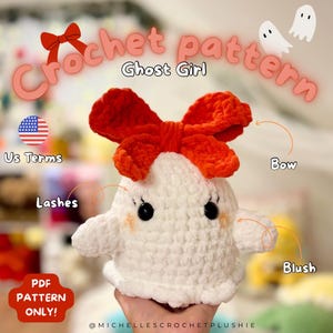 Könnte beinhalten: Ein weißes gehäkeltes Geisterplüschtier mit einer orangefarbenen Schleife, schwarzen Augen und Rouge. Der Text "Crochet pattern Ghost Girl" wird über dem Plüschtier angezeigt. Das Bild enthält auch den Text "PDF pattern only!" und "US Terms".