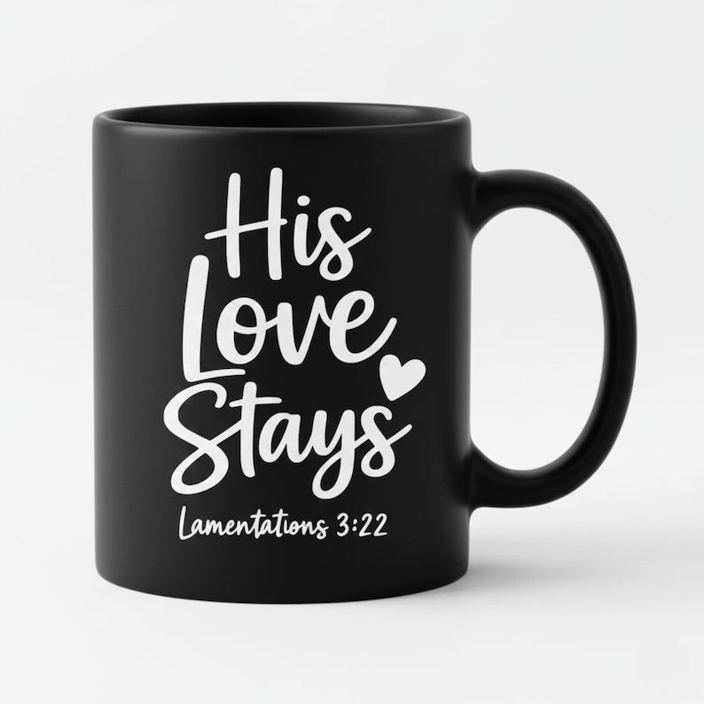 K&ouml;nnte beinhalten: Schwarze Keramik-Tasse mit wei&szlig;em Schriftzug "His Love Stays" und einem Herzsymbol. Der Text "Lamentations 3:22" ist darunter gedruckt. Die Tasse hat einen gebogenen Henkel.
