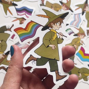 May include: A sticker featuring a cartoon character wearing a green hat and carrying a rainbow flag. The character is running and smiling. The sticker is on a white background.
