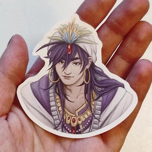 Peut inclure: Un autocollant représentant une illustration dessinée à la main d'une personne aux longs cheveux violets portant un turban blanc avec un motif de plumes colorées, une robe violette et des bijoux en or avec des pierres précieuses rouges.