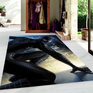May include: Black and blue rug with a graphic of a superhero in a crouching pose.