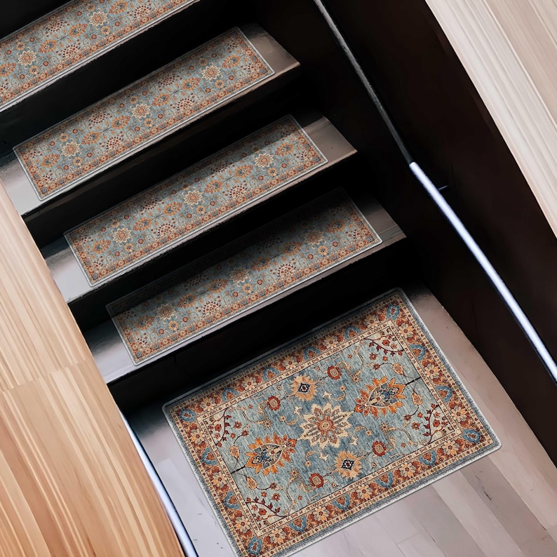 May include: A set of stair treads with an ornate, floral pattern in shades of blue, orange, and beige. The treads are rectangular and placed on wooden stairs, creating a decorative and functional element for home decor.