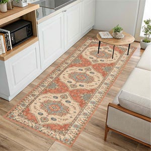 May include: A rectangular runner rug with an ornate, traditional design. The rug features a central pattern in shades of peach, cream, and blue, with a detailed border. The rug is placed on a wooden floor in a kitchen setting.
