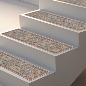 May include: Stair treads with a traditional Persian rug design. The treads feature a blue background with floral and geometric patterns in shades of orange, brown, and cream. The treads are rectangular and placed on white stairs.