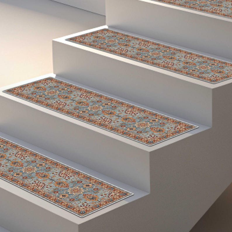 May include: Stair treads with a traditional Persian rug design. The treads feature a blue background with floral and geometric patterns in shades of orange, brown, and cream. The treads are rectangular and placed on white stairs.