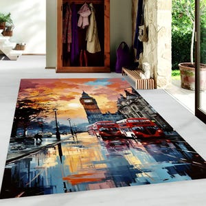 May include: A colorful painting of a London street scene with Big Ben, red double-decker buses, and a sunset sky. The painting is on a rug with a textured surface.
