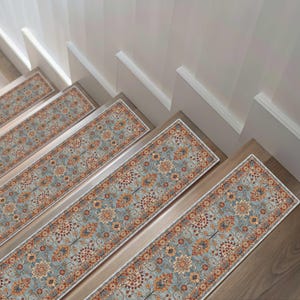 May include: Stair treads with a traditional floral pattern in shades of blue, orange, and red. The stair runners are rectangular and have a white border. The treads are installed on wooden stairs.