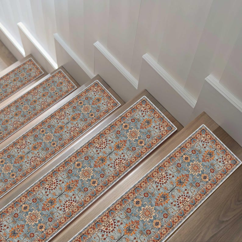 May include: Stair treads with a traditional floral pattern in shades of blue, orange, and red. The stair runners are rectangular and have a white border. The treads are installed on wooden stairs.